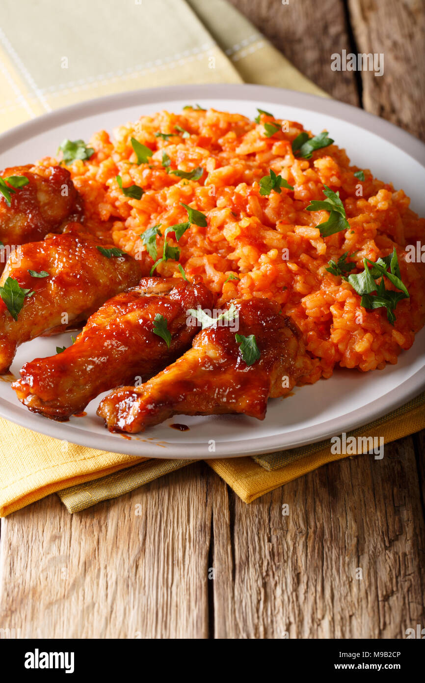 West African food: Jollof Reis mit Fried Chicken wings Close-up auf einem Teller. Vertikale Stockfoto