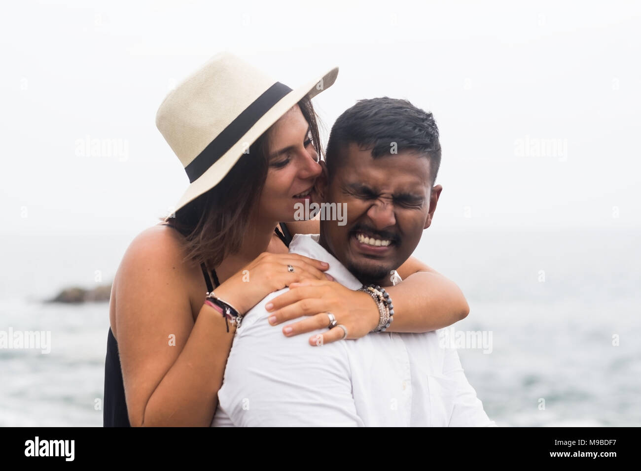 Kaukasische schöne Frau umarmt sie Mann und beißt sein Ohr ein wenig. Konzept der wahren Liebe und lustige Momente im Leben der Familie Stockfoto