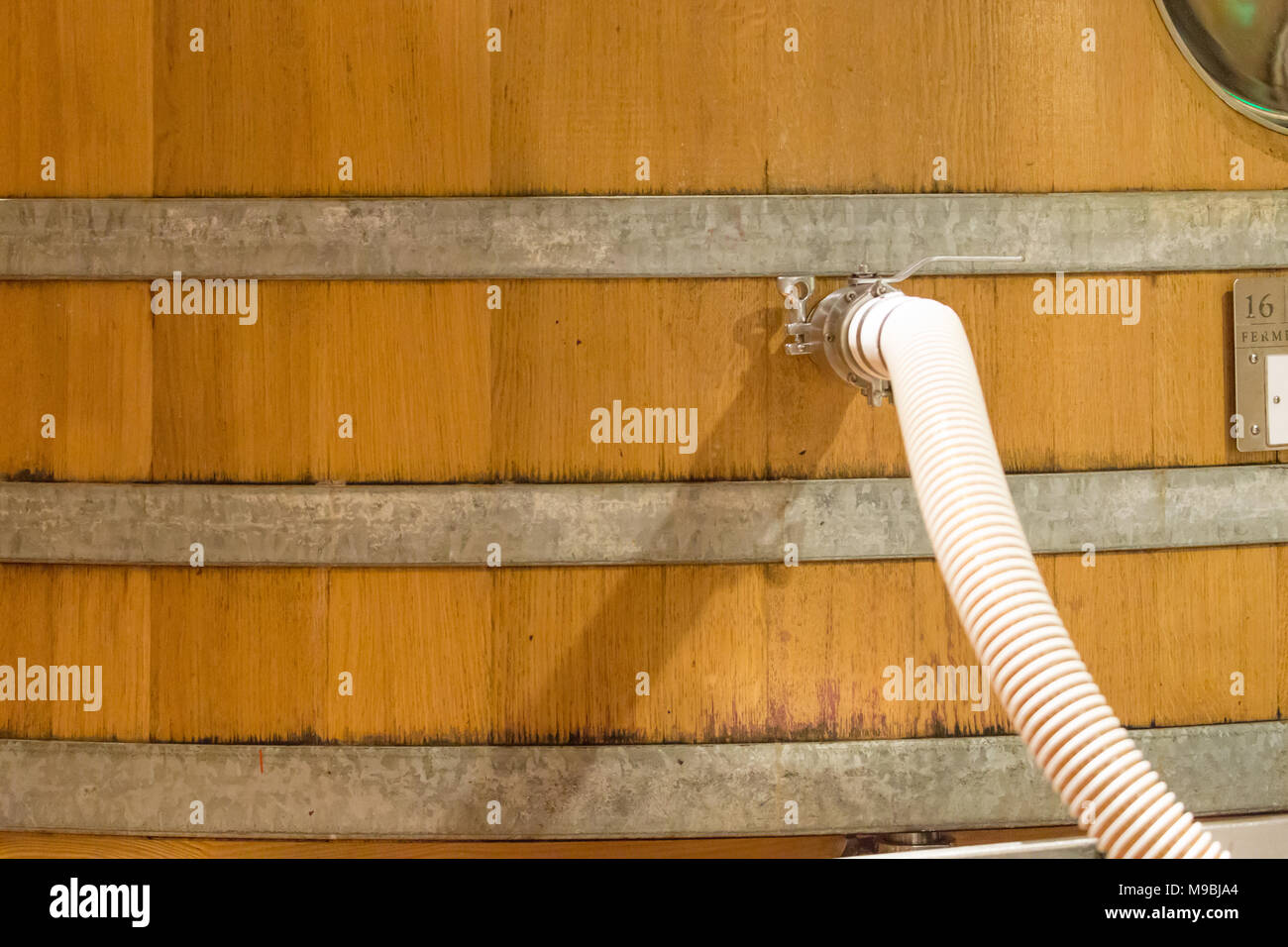 Ein Schlauch, der in einen Weintank in einem Weingut geht Stockfoto