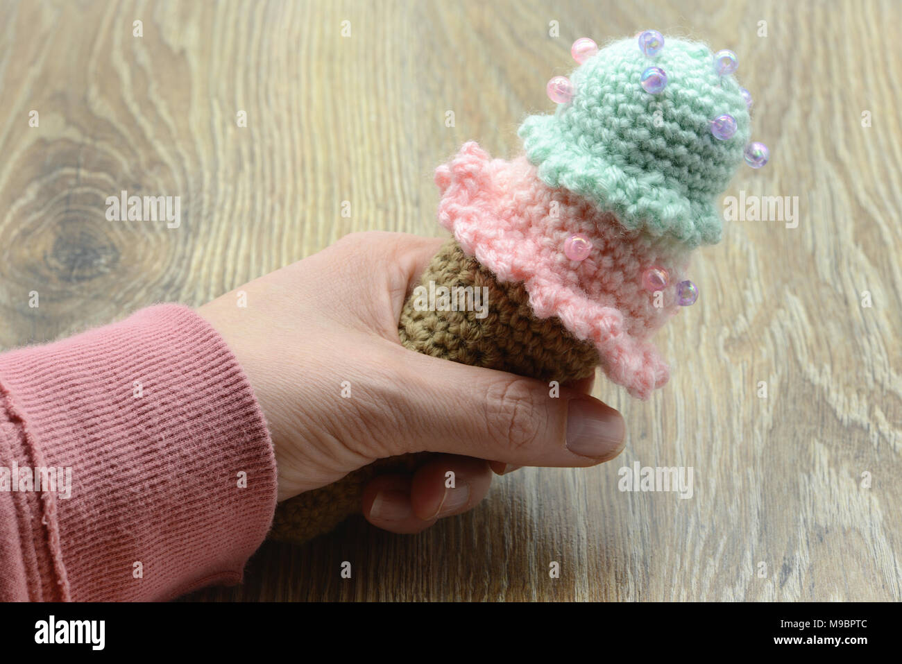 Hand, die Häkeln Eiswaffel aus Wolle auf Tisch Hintergrund Stockfoto