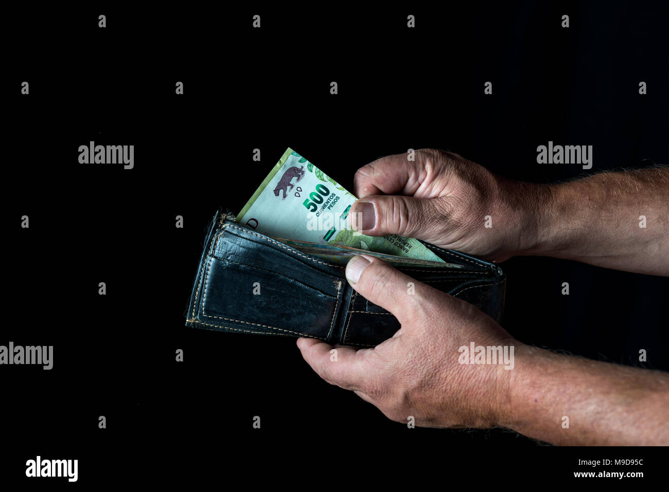 Die Hände des Menschen einen fünfhundert Argentine Peso Wechsel aus einem Portemonnaie, auf schwarzem Hintergrund Stockfoto