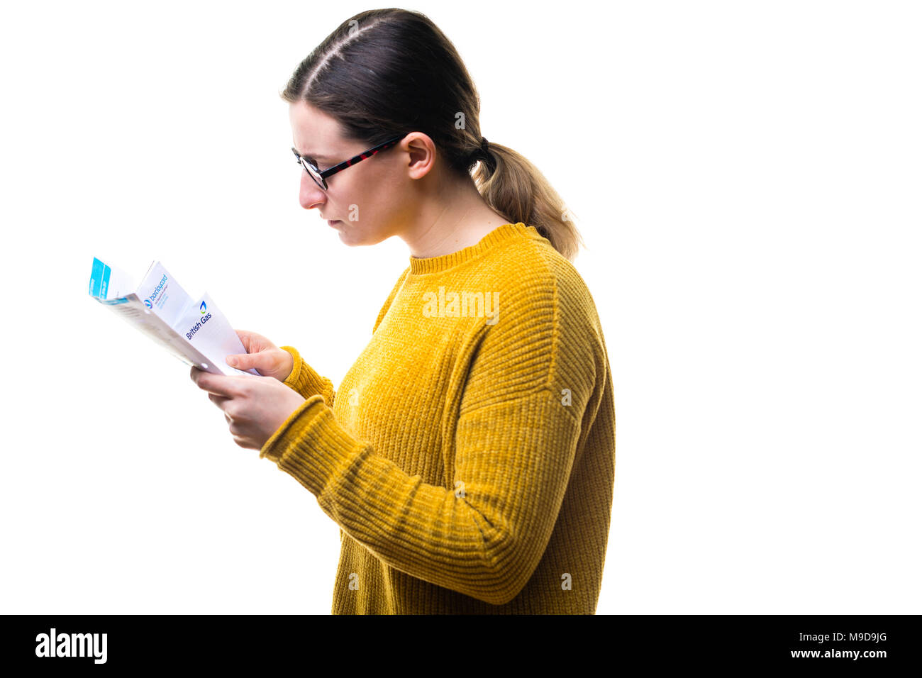 Geldsorgen und persönliche Finanzen: Eine Junge kaukasier Frau Mädchen mit einem gelben Pullover Pullover, an ihrer Rechnungen suchen und über das Zahlen von inländischen Stromversorgung Gebühren besorgt, Großbritannien Stockfoto