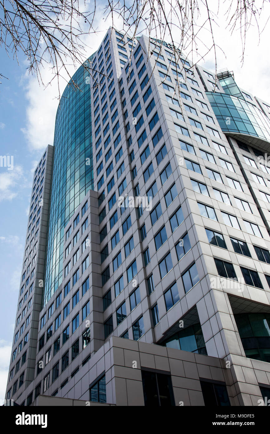 Hohes blaues Gebäude im Herzen der Stadt. Könnte ein Bürogebäude oder ein Apartment. Natürliche Gestaltung der Bäume rund um das Gebäude. Stockfoto