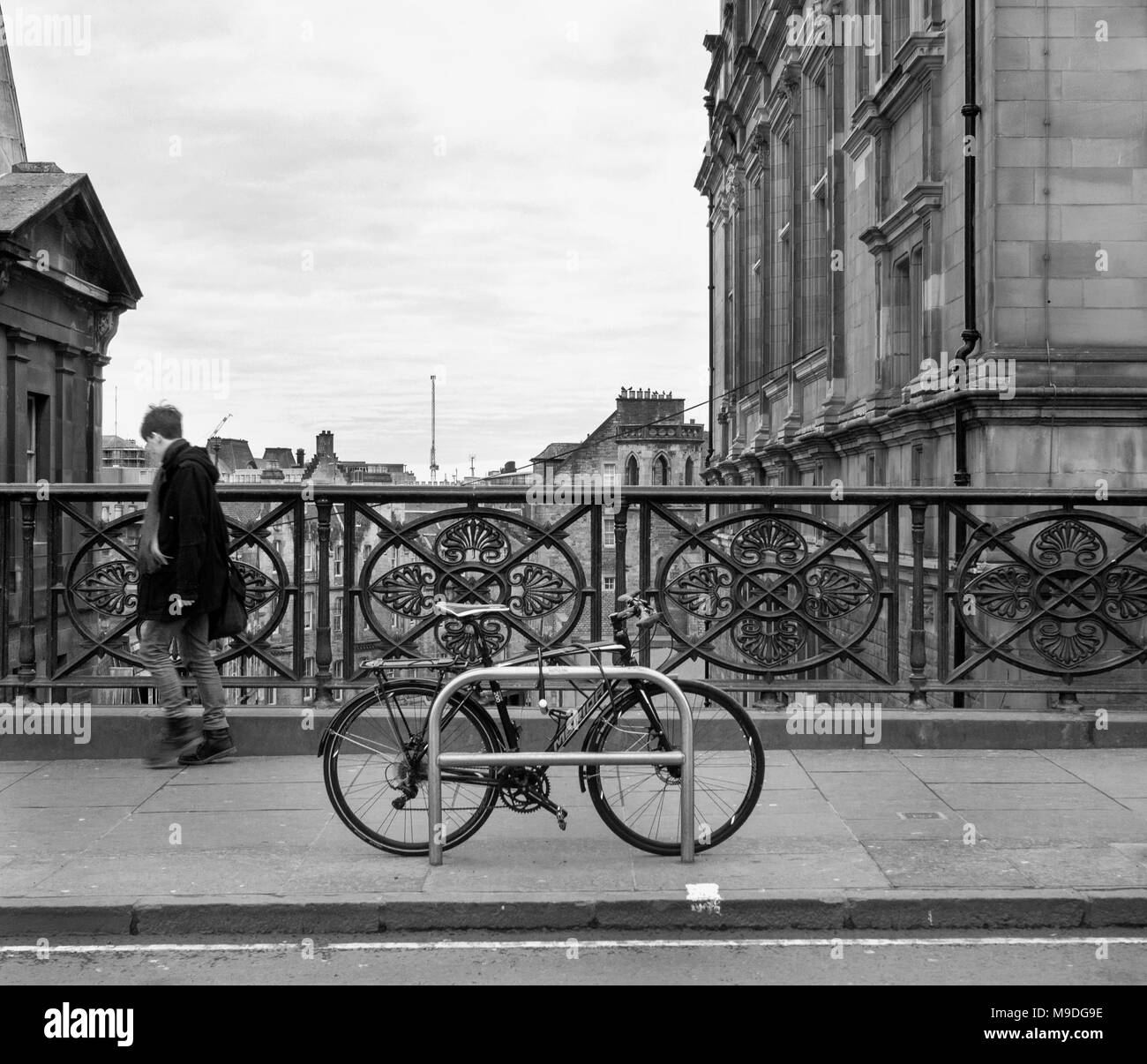 EDINBURGH, Schottland - 5. FEBRUAR 2018: Mann zu Fuß vorbei an einem Fahrrad auf George IV Bridge. Stockfoto