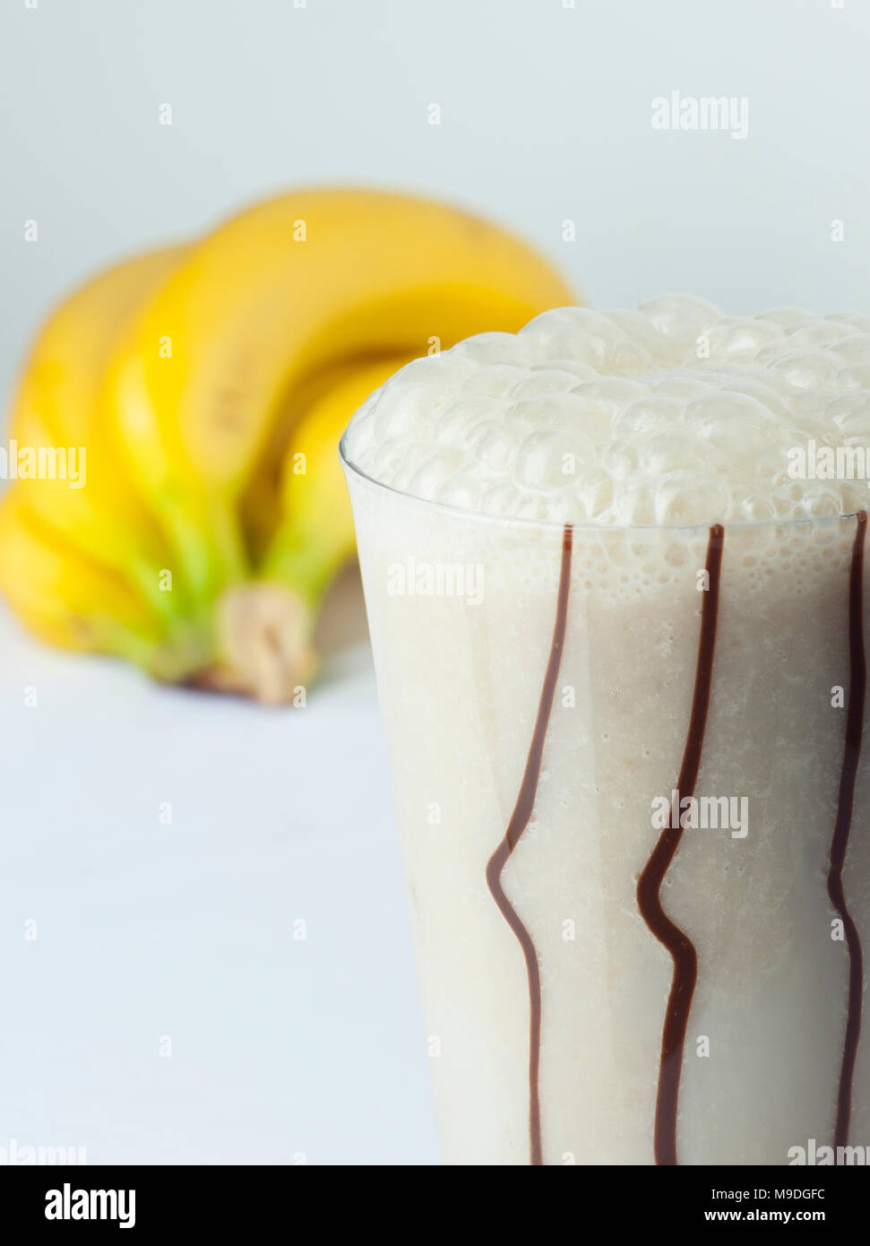 Ein Glas Banane und Milch coctail Nahaufnahme mit voller Früchte im Hintergrund Stockfoto