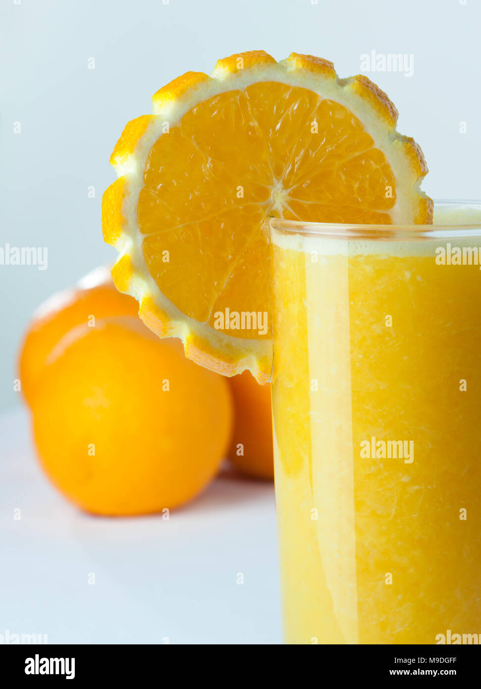 Ein Glas Orangensaft aus der Nähe mit einer Scheibe und Früchte im Hintergrund Stockfoto