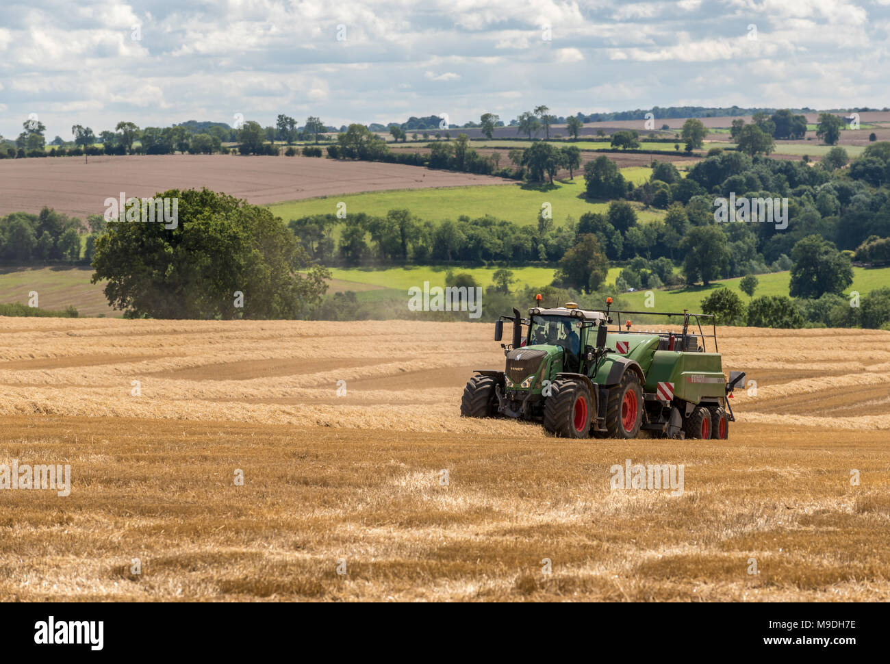 Traktor ausschöpfenden Stroh in einer frisch geernteten Weizen Feld an einem sonnigen Tag Stockfoto