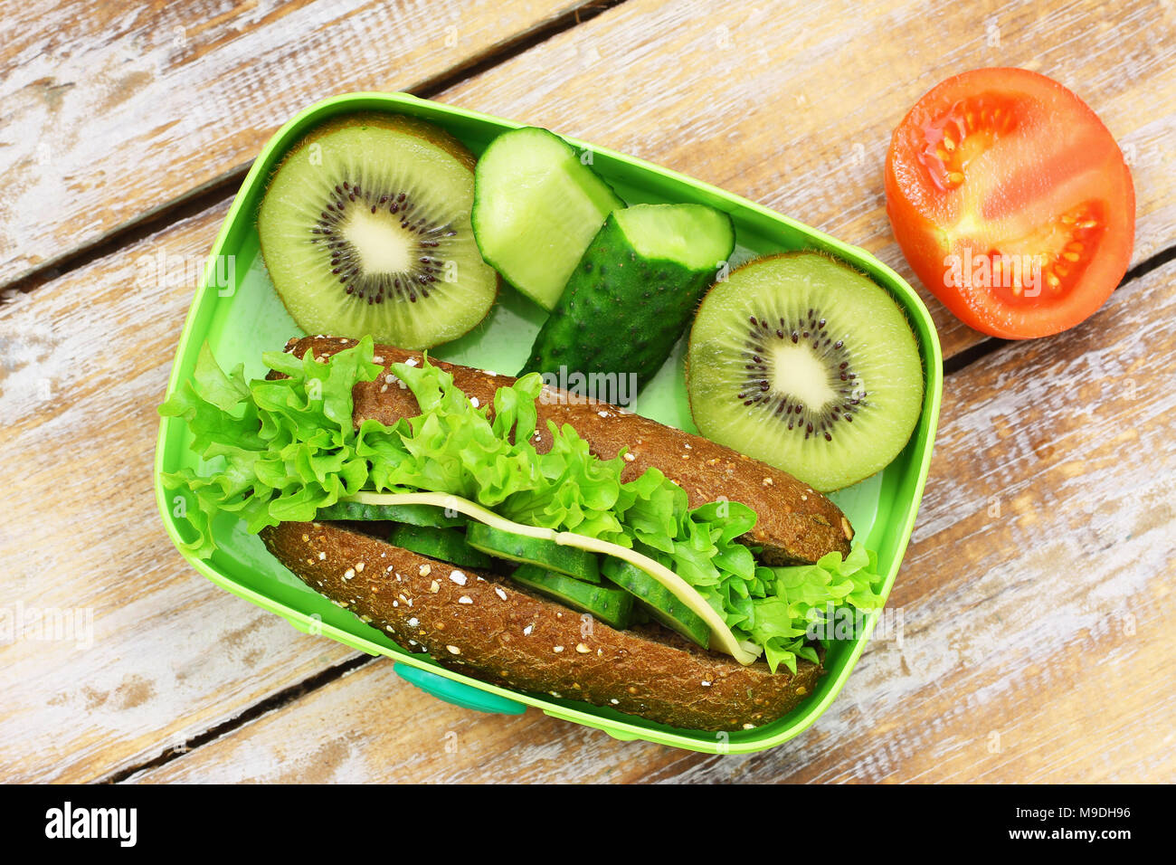 Gesunde Schule Lunch Box mit braunen Käse Sandwich, Gurken Sticks und Kiwi Stockfoto