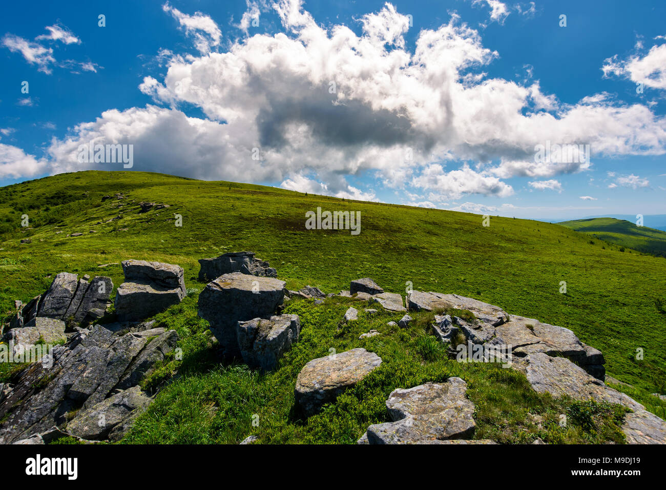 Riesige Wolke hinter dem Hügel steigen. wunderschöne Berglandschaft mit Felsbrocken auf grashängen Stockfoto