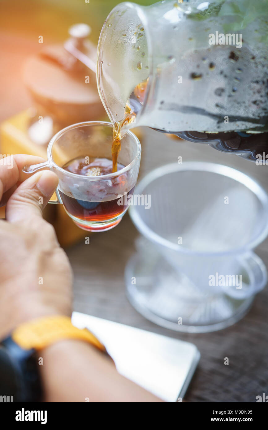 Nahaufnahme der Barista Hände Kaffee eine Tasse Kaffee einzuschenken. Selektiver Fokus auf Hände, die Tasse Kaffee. Stockfoto
