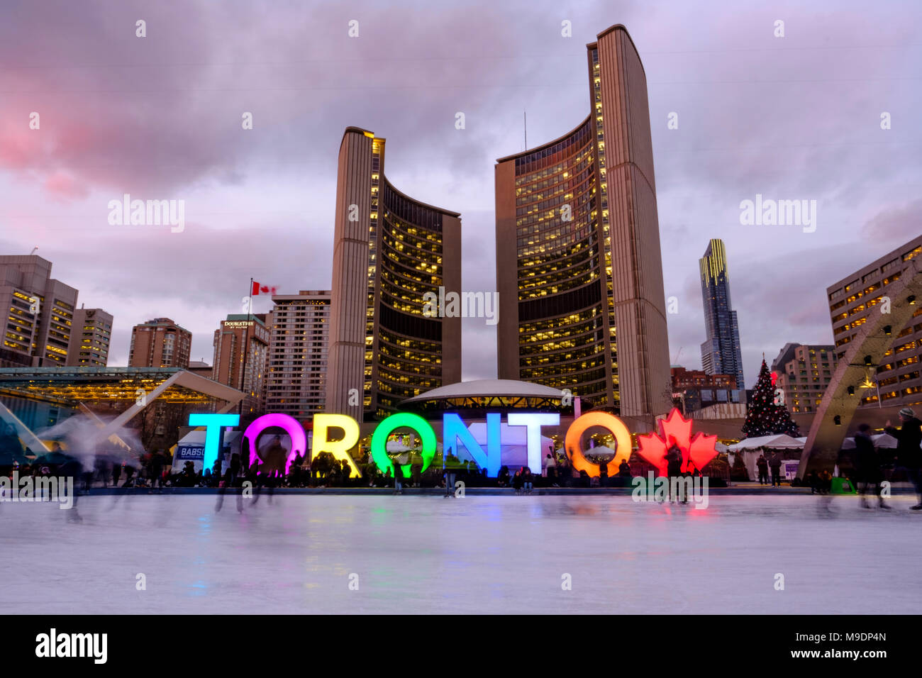 Toronto City Hall, Nathan Phillips Square im Winter, Eislaufbahn in der Abenddämmerung, Toronto Schild, Menschen in der Innenstadt von Toronto, Ontario, Kanada. Stockfoto