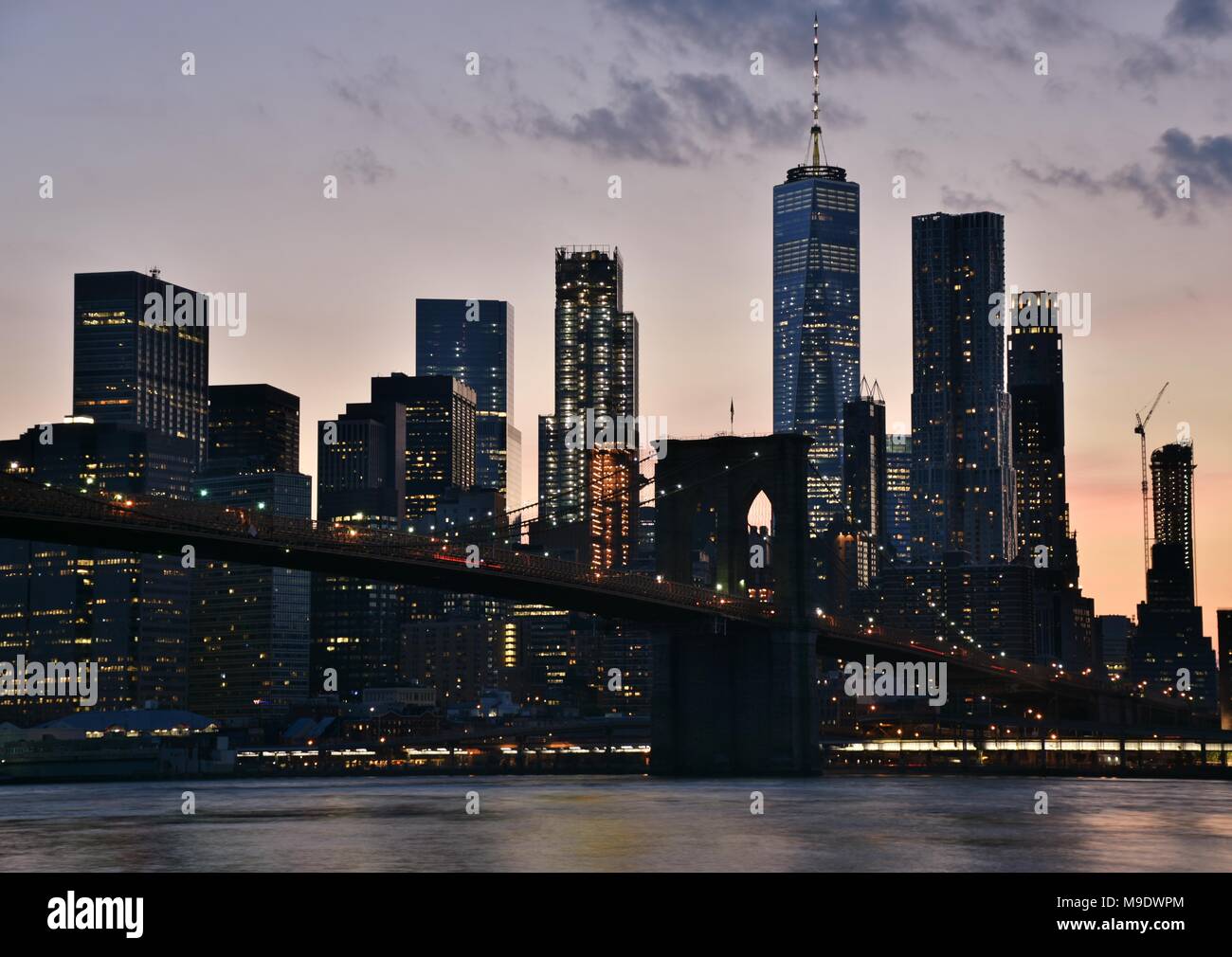 Der Freedom Tower, der Wall Street, und die Skyline von Manhattan aus Brooklyn bei Sonnenuntergang. Stockfoto