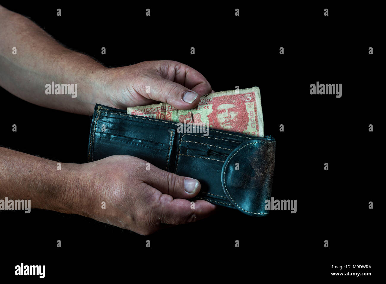 Die Hände des Menschen einen drei kubanische Peso Wechsel aus einem Portemonnaie, auf schwarzem Hintergrund Stockfoto
