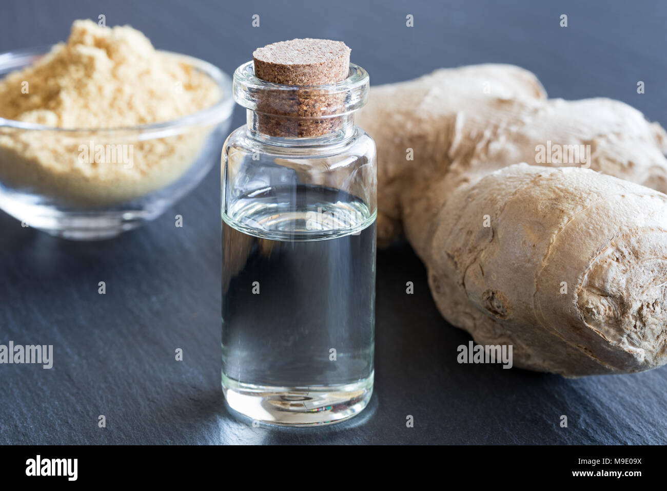Eine Flasche Ingwer ätherisches Öl mit frischen und getrockneten Ingwer im Hintergrund Stockfoto