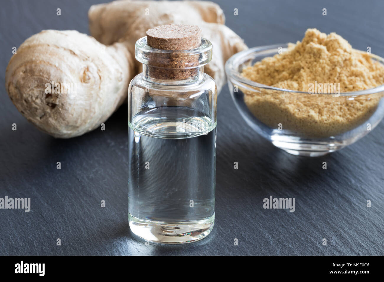 Ingwer ätherisches Öl in eine Flasche, die mit frischen und getrockneten Ingwer im Hintergrund Stockfoto