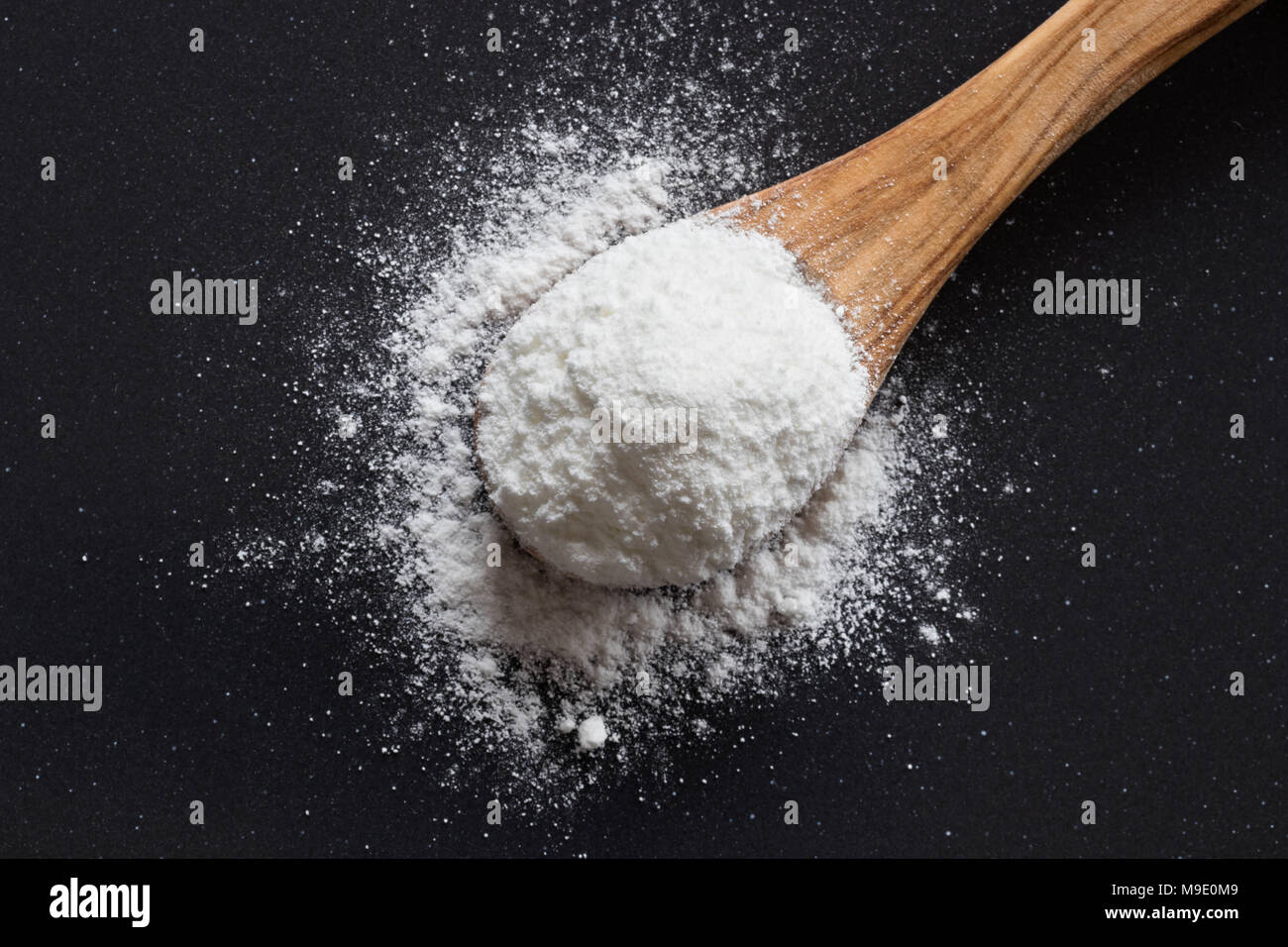 Natron auf einer hölzernen Löffel auf dunklem Hintergrund, Ansicht von oben, Natriumbikarbonat, Pulver, Natur, Kochen, Backen, Stockfoto