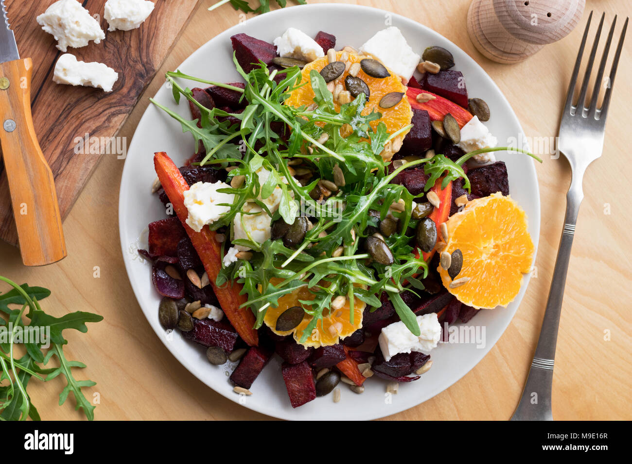 Salat gebackene Rote Beete und Karotten, Orangen, frisch und Rucola, Ziegenkäse, Gerösteter Kürbis- und Sonnenblumenkerne. Ansicht von oben. Stockfoto