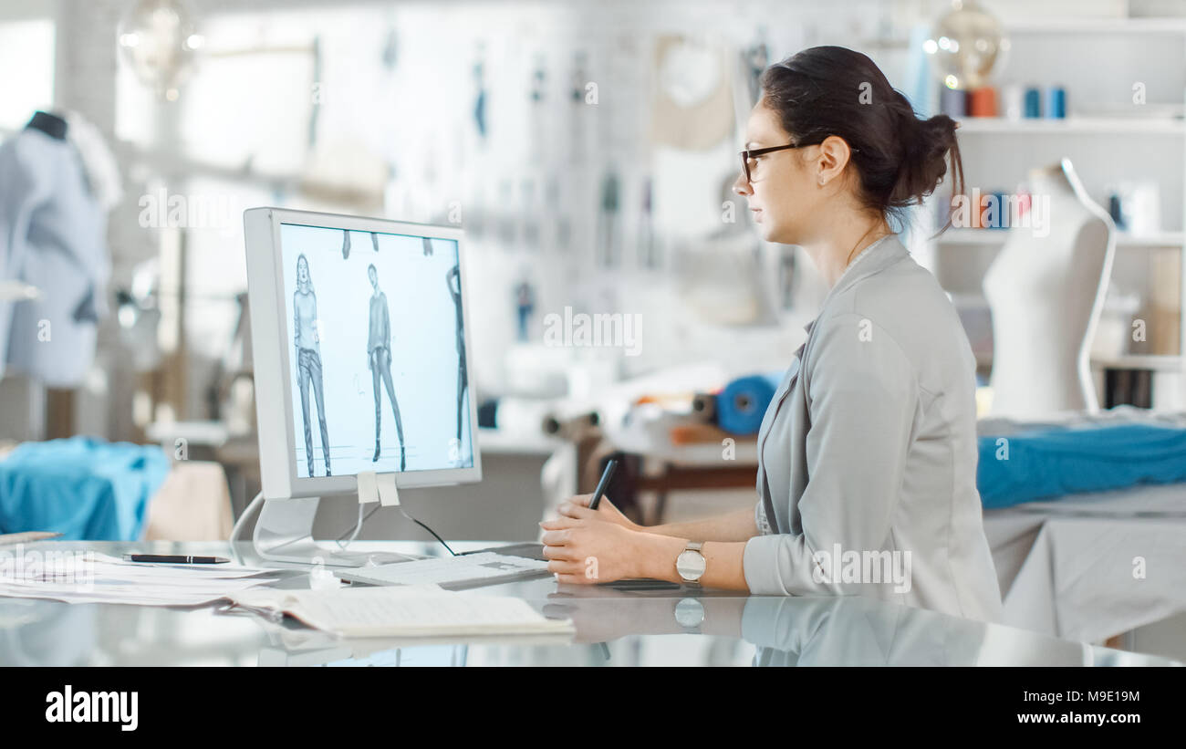 Schöne Mode, Designer, sitzt an ihrem Schreibtisch vor dem Computer, mit digitalen Zeichentablett. Ihr Studio ist sonnig, voll von bunten Details Stockfoto