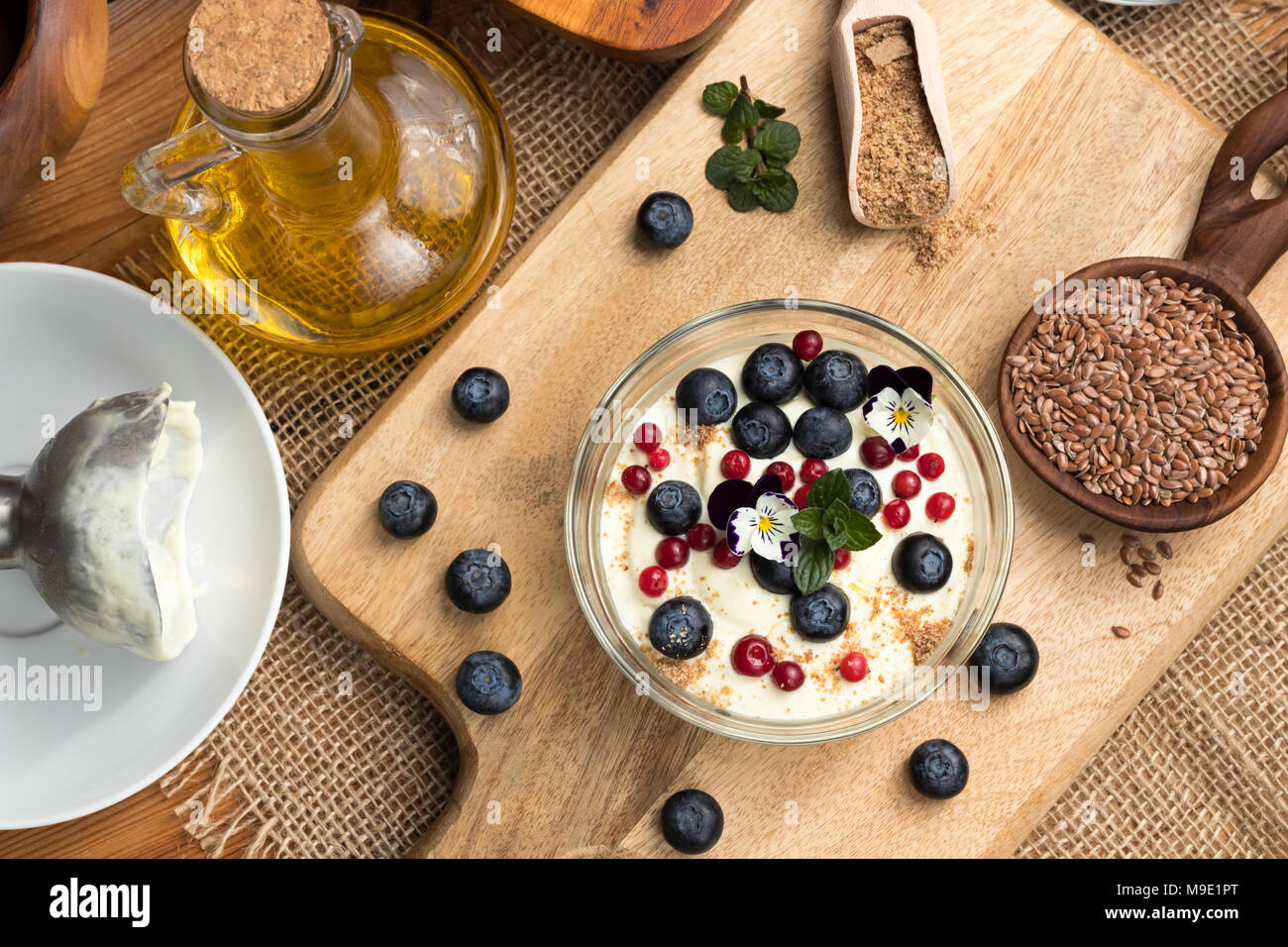 Hüttenkäse Gemischt mit Leinsamen öl, mit frischen Blaubeeren überstieg, gefroren wilde Preiselbeeren, essbare Blumen und Boden Leinsamen Stockfoto