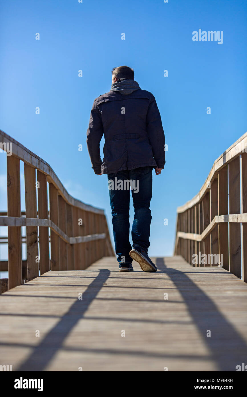 Ansicht von hinten von einem Mann zu Fuß auf hölzernen Boardwalk. Stockfoto