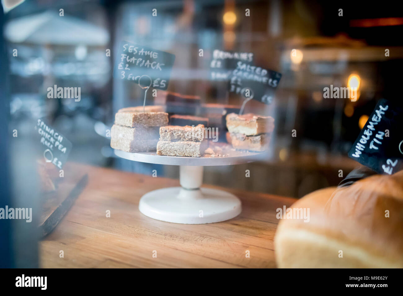 Flapjack und Kuchen Auswahl auf einem Display auf einem Kuchen stehen in einer Bäckerei Fenster in Großbritannien Stockfoto
