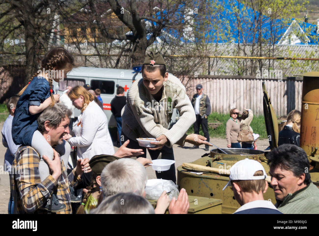 Mstyora, Russia-May 9,2015: Jugendlicher in oversea Cap überlagert Porridge aus Feld Küche bei festlichen Tag des Sieges in Stadt Mstyora, Russland Stockfoto