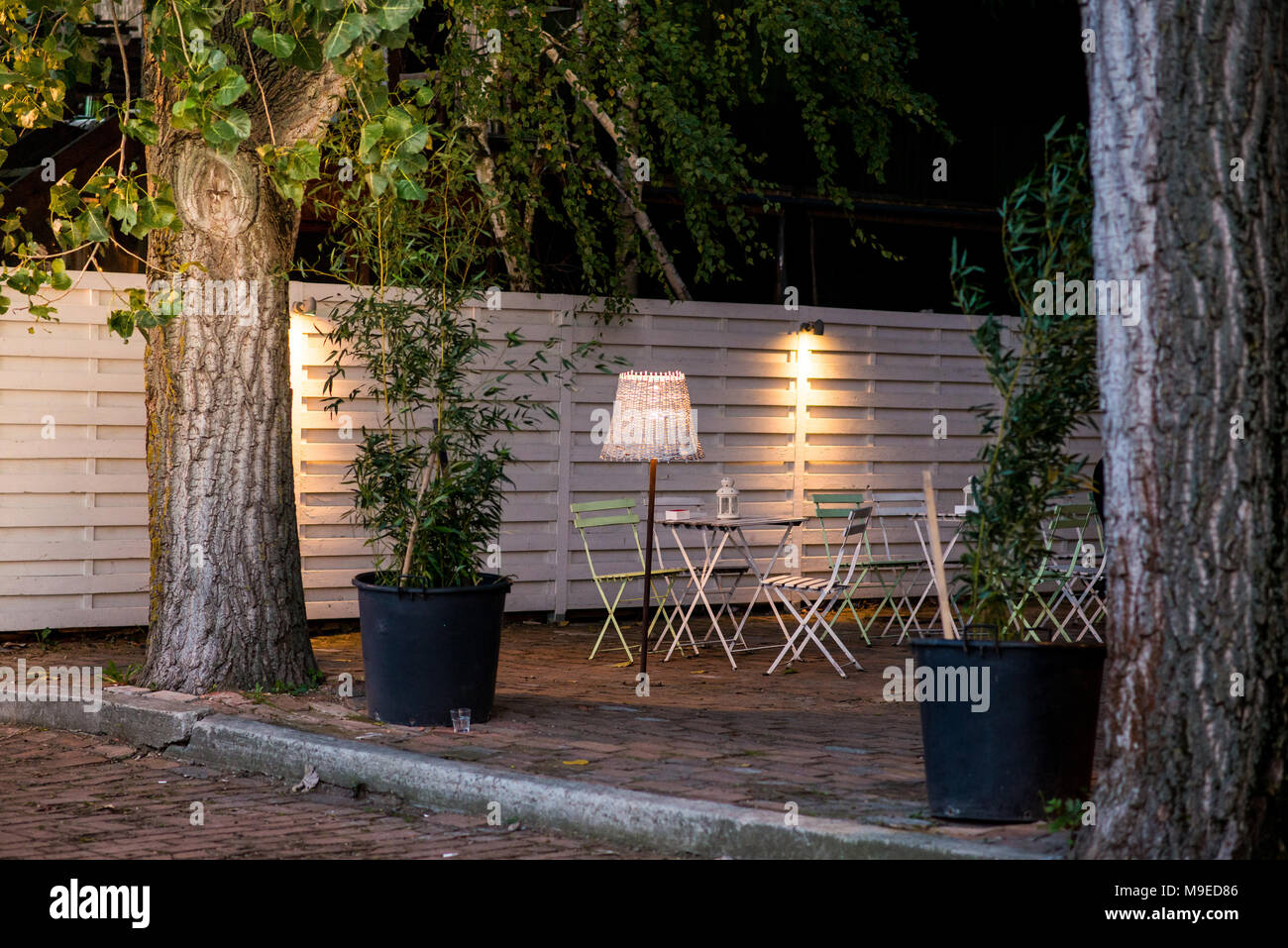 Leere Cafe mit Stühlen und Tischen zwischen Bäumen in der Nacht Stockfoto