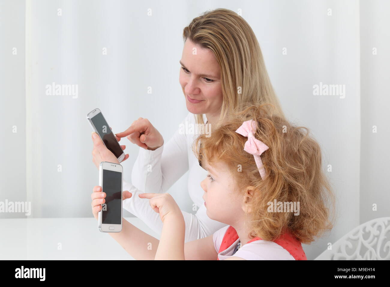 Eine Mutter, die ihr Kind Digitalisierung mit Smartphone Stockfoto