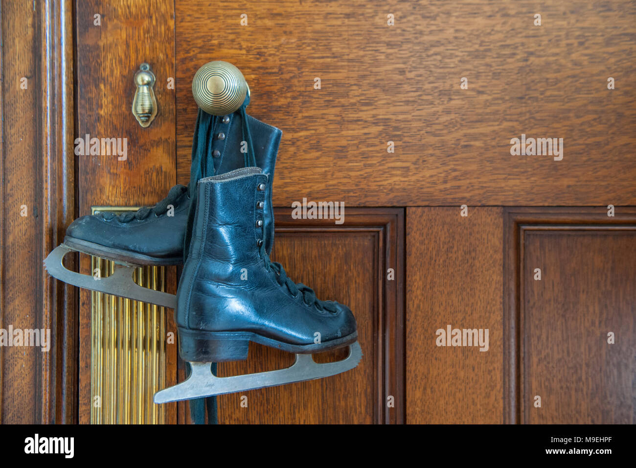 Einige alte Kinder oder Damen Schlittschuhe hängend an einer Tür in einem viktorianischen Haus Griff Stockfoto