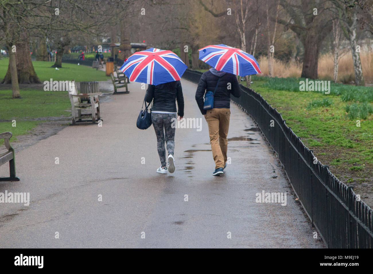 Ein paar Spaziergang durch St. James's Park mit Union Jack Schirme an einem kalten, grauen, nassen Tag in London. Stockfoto