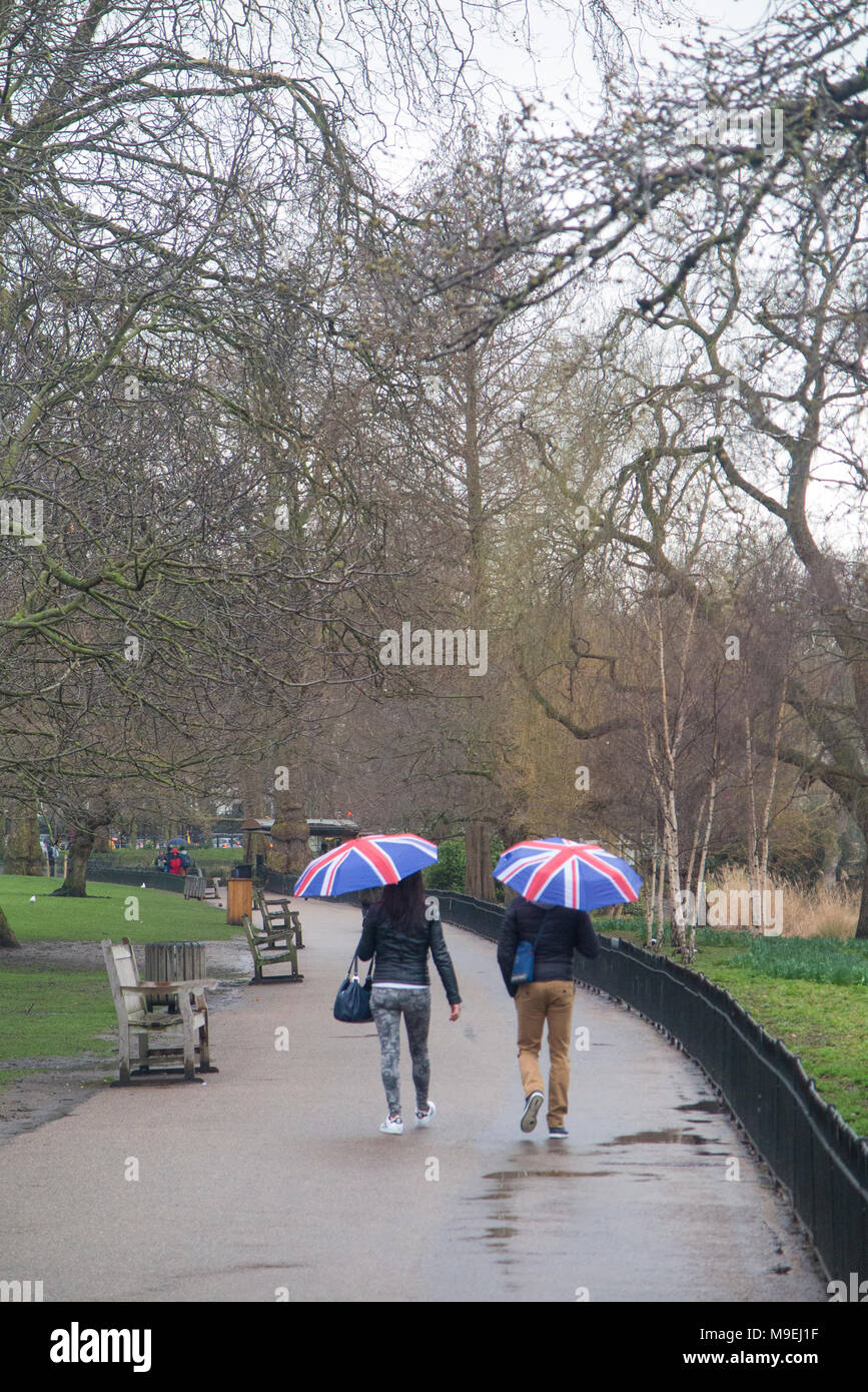 Ein paar Spaziergang durch St. James's Park mit Union Jack Schirme an einem kalten, grauen, nassen Tag in London. Stockfoto