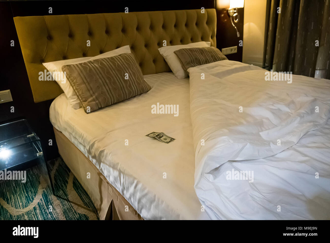 Dollar auf dem Bett im Zimmer. Trinkgeld für den Zimmerservice im Hotel. ein Dollar Bill auf einem weißen Blatt. Tipps am Bett für die Haushälterin im Hotel. Stockfoto