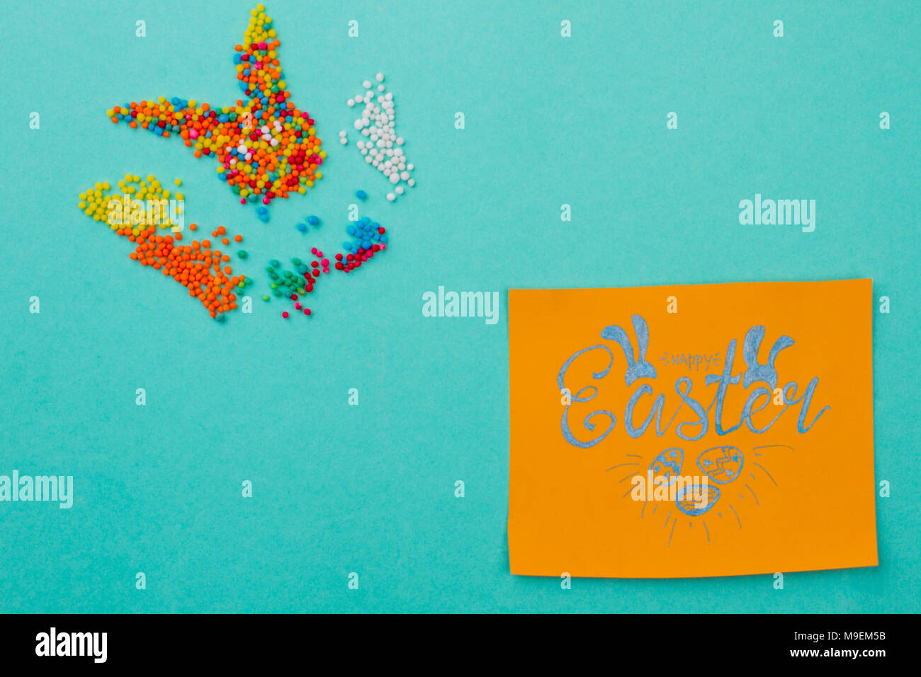 Ostern Grusskarten auf Türkisfarbenem Hintergrund. Bunte Bonbons in einer Form der Osterhase. Handschriftliche congratulatory Karte mit Ostern. Stockfoto