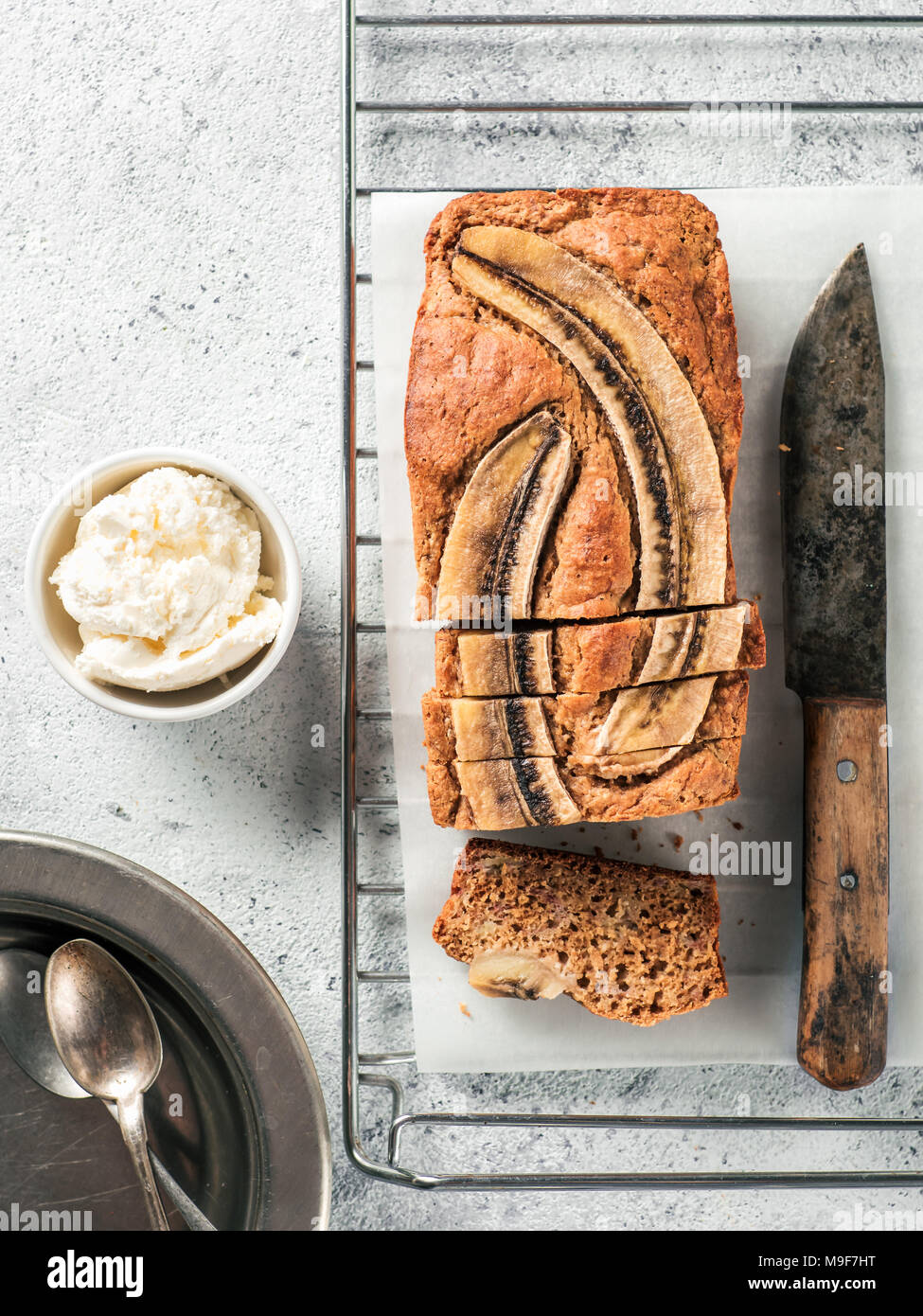 Butter, Zucker-freien Bananenbrot mit Hafermehl, weiche Quark und Honig. Blick von oben auf die bananenscheiben Brot auf grauzement Hintergrund. Ideen und Rezepte für gesunde Ernährung Frühstück. Vertikale. Stockfoto