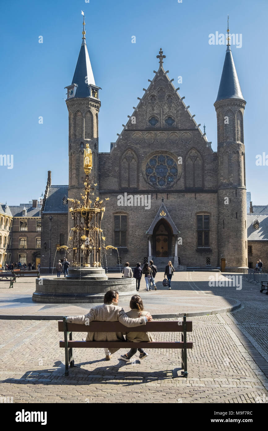 Junger Mann und Frau sitzt auf der Bank außerhalb der Ridderzaal (Rittersaal) Gebäude, der Binnenhof, Den Haag (Den Haag), in den Niederlanden. Stockfoto