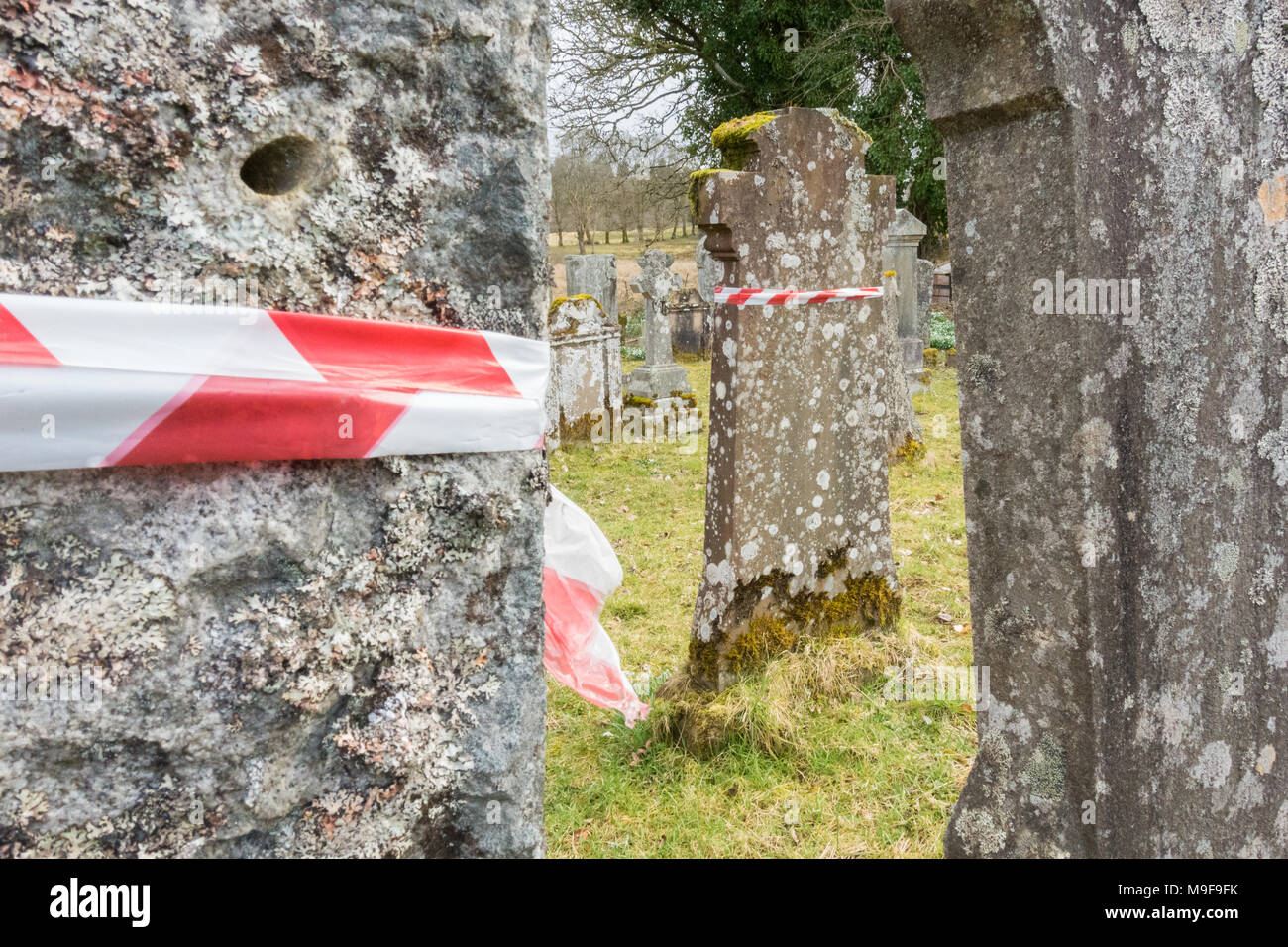 Memorial Sicherheit - rot-weißen Absperrband um Grabsteine in Aberfoyle Alte Pfarrei Kirchhof, Schottland, UK gewickelt Stockfoto