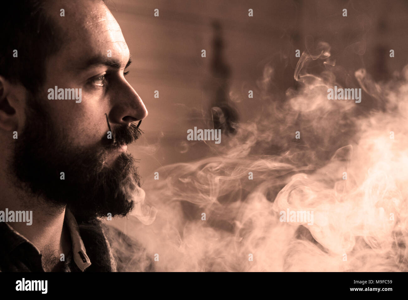 Mann mit Bart und Mustages Vaping eine elektronische Zigarette. Vaper  Hipster Rauch Vaporizer und Exhals Rauch Ringe Stockfotografie
