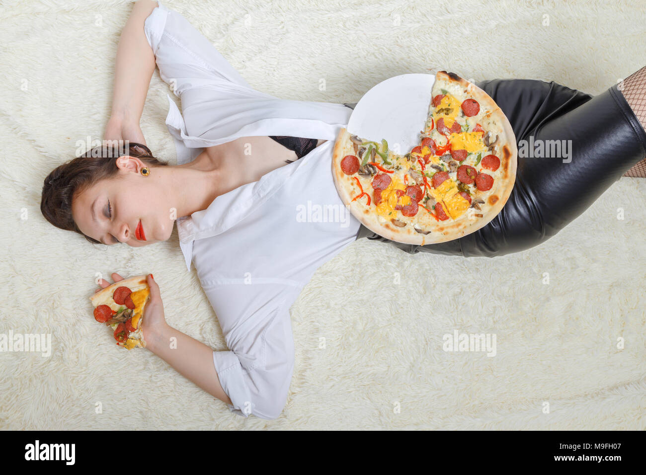 Überessen Frau mit Stücken von Pizza auf weißem Hintergrund Stockfoto