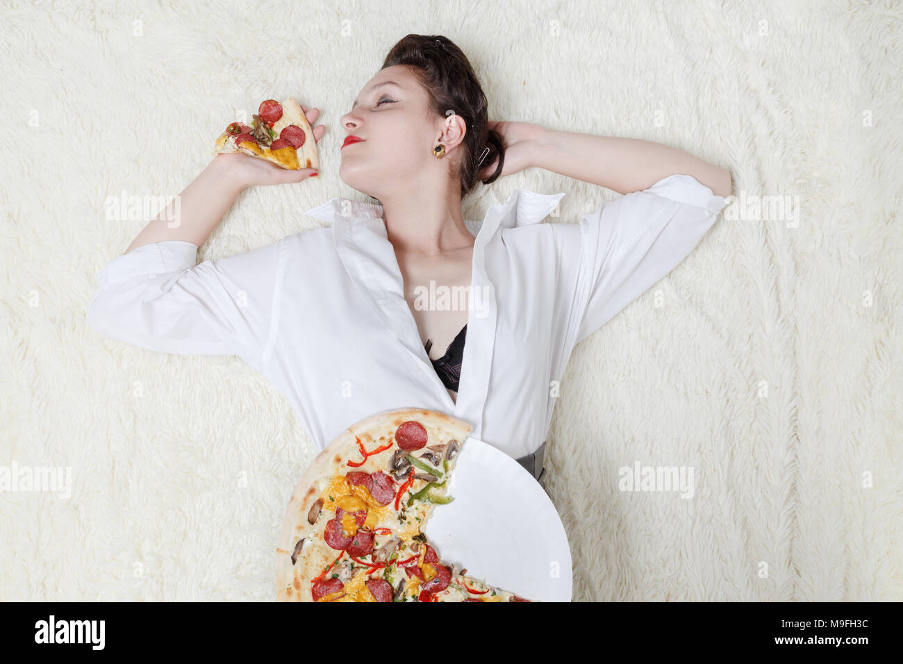 Überessen Frau mit Stücken von Pizza auf weißem Hintergrund Stockfoto