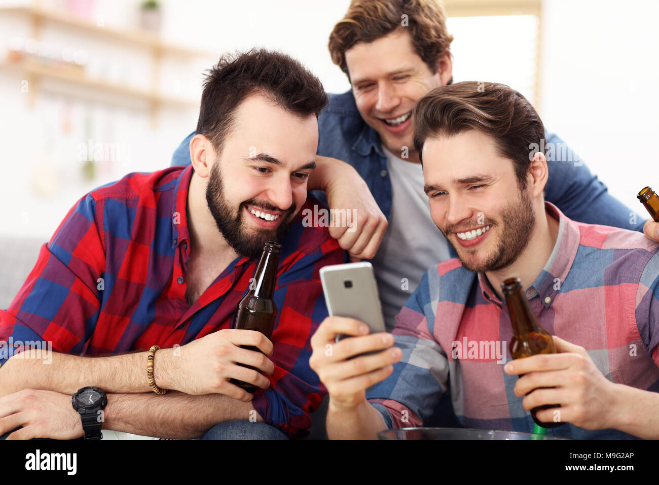 Gruppe von Freunden beobachten Smartphone sitzen auf einer Couch im Wohnzimmer zu Hause Stockfoto