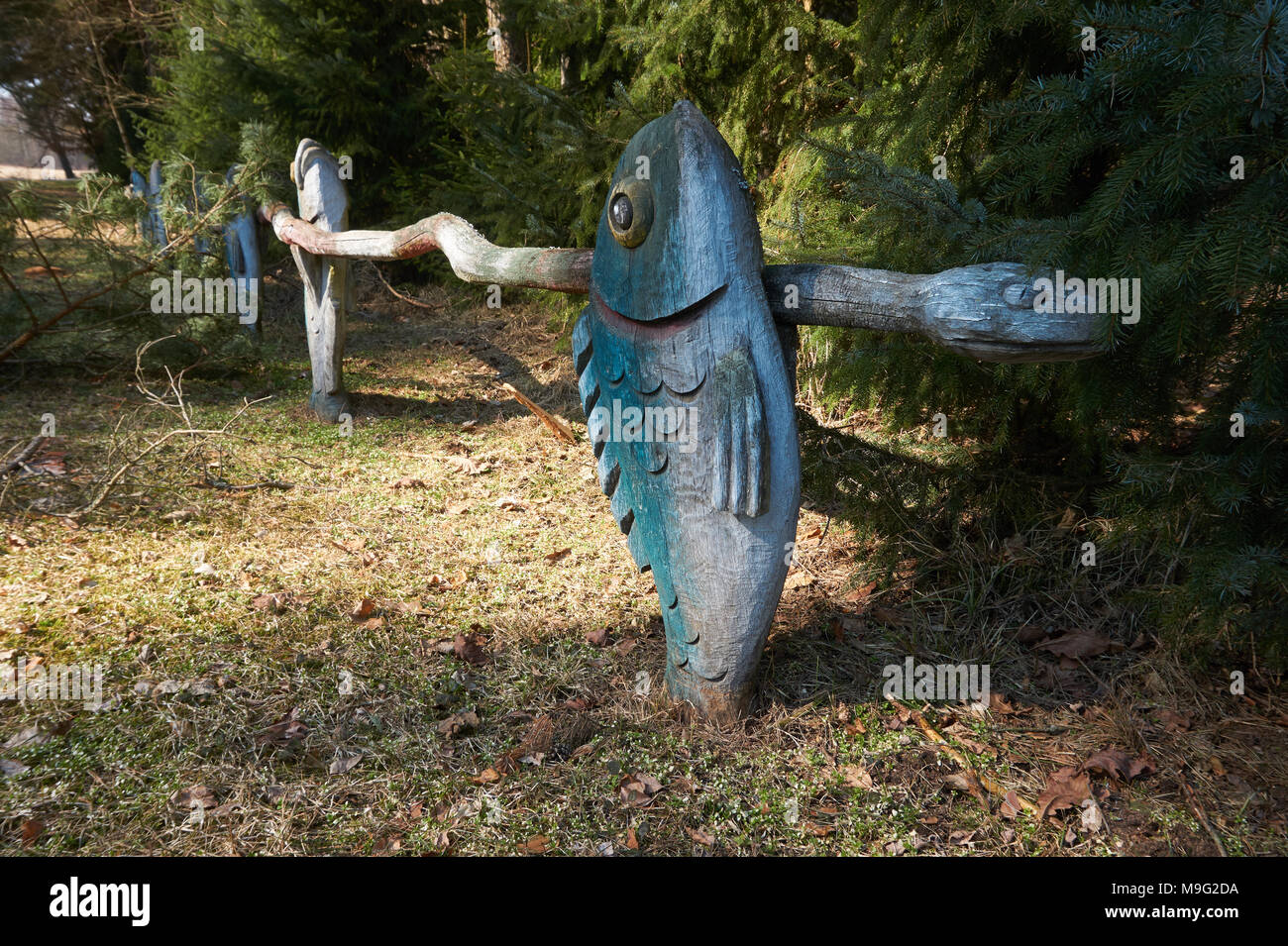 Zaun Dekorationen. Bunte Zaun in der Nähe der grünen Tannen. Fisch und Schlange. Stockfoto