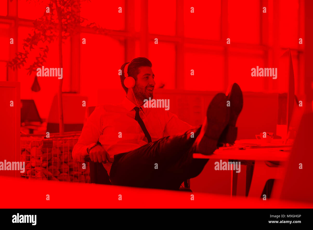 glückliche junge arabische Geschäftsmann mit Bart Musik hören über Kopfhörer in modernen Startup-Büro Stockfoto