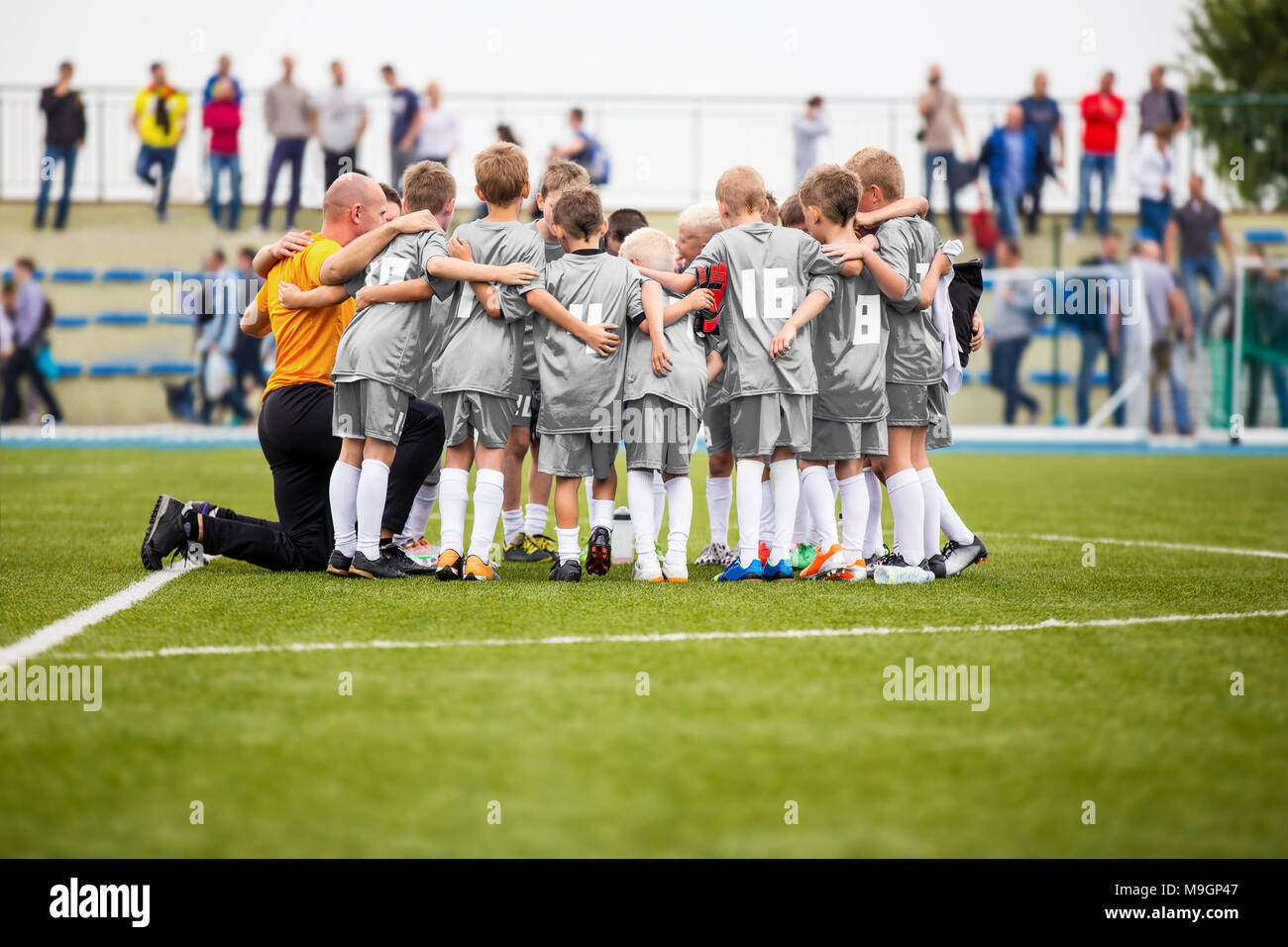 Fußball-Coaching. Jungen in Pep Talk mit Trainer vor dem Turnier. Kids Soccer Academy Team auf dem Spielfeld. Youth Soccer Coach Coachi Stockfoto