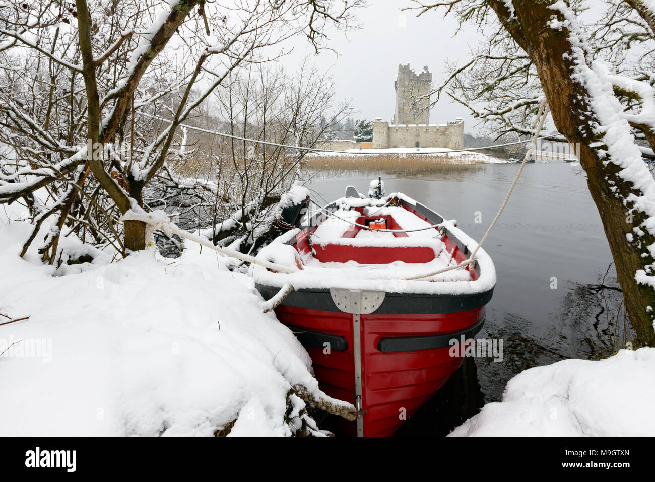 Rotes Boot im Lough Leane See am Ross Castle Killarney im Winterschnee im Killarney National Park, County Kerry, Irland Stockfoto