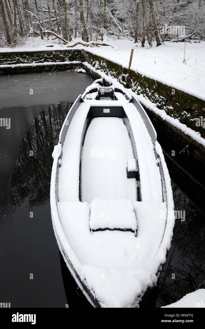 Ein einsames Boot, das mit Schnee bedeckt ist, in einem kleinen See Stockfoto