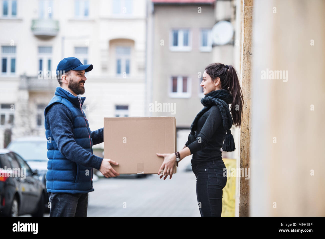 Junge Frau Paket empfangen von Lieferung Mann an der Tür - Kurier Service  Konzept Stockfotografie - Alamy