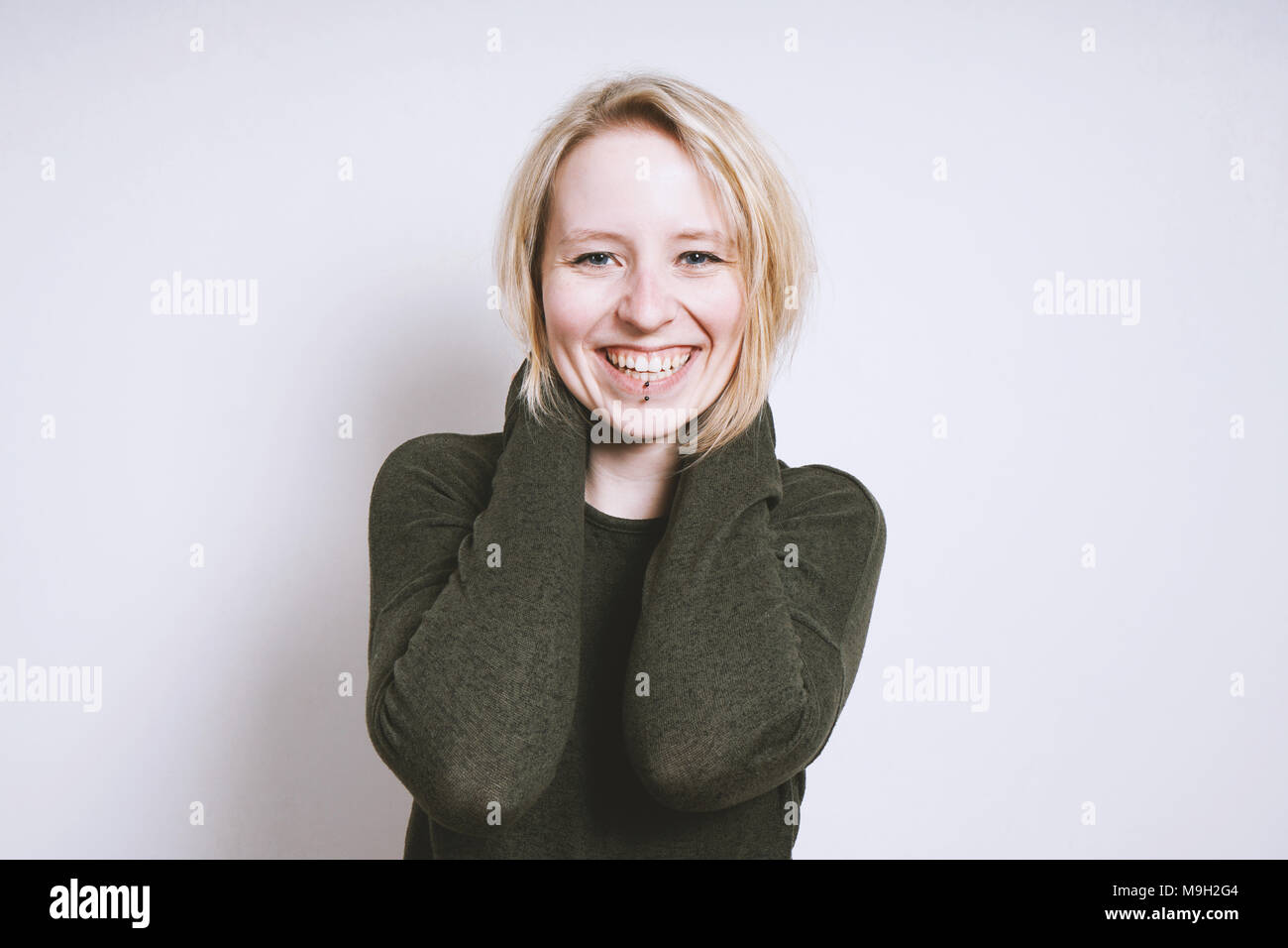 Gerne blonde junge Frau mit toothy Lächeln Stockfoto