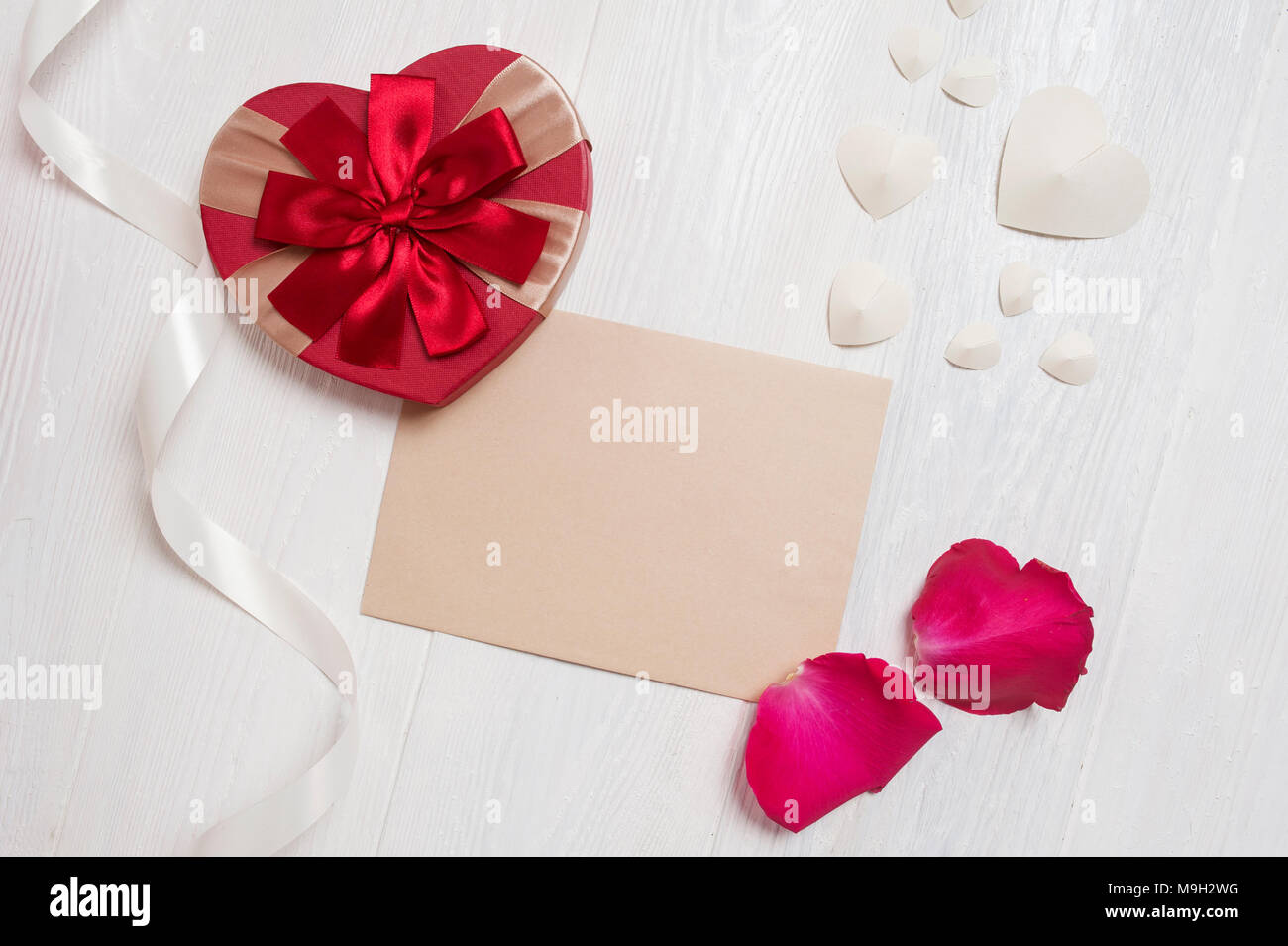 Mockup Brief mit einem Geschenk in Form von einem Herz und einer Blüten von Rosen. Grußkarte für Valentines Tag mit Platz für Ihren Text. Flach, Ansicht von oben Foto Mock up Stockfoto