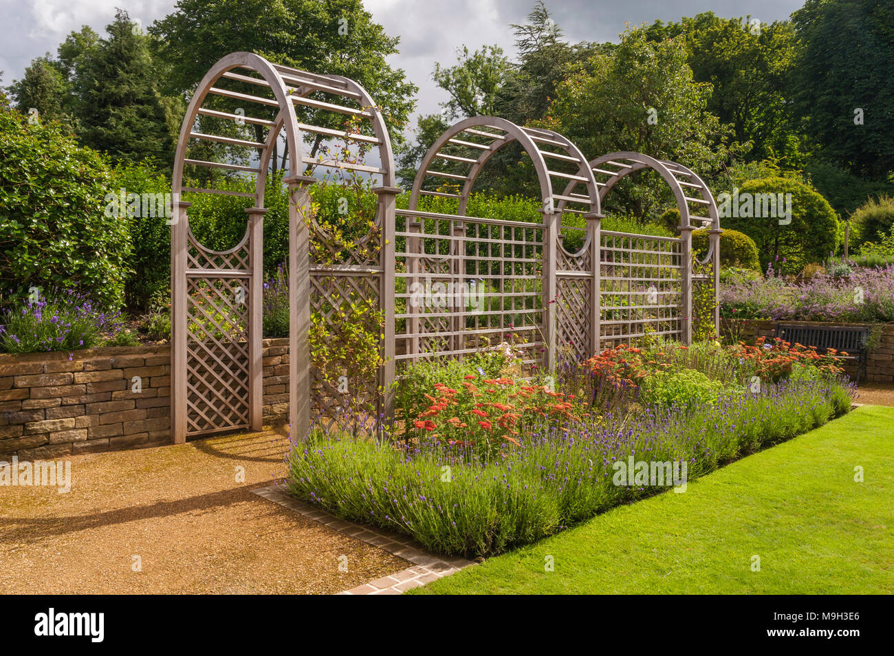 Sommer Blick auf die sonnenbeschienenen Tunnel Laube & bunten Blumenrabatten - Schöne, gestaltet, gepflegten, traditionellen Garten, West Yorkshire, England, UK. Stockfoto