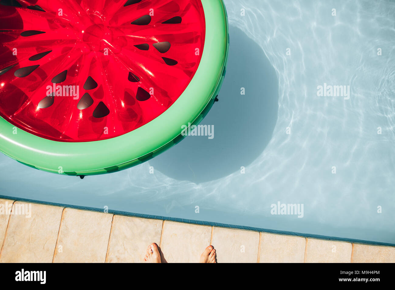 Blick von oben auf die bunte aufblasbare Wassermelone schwimmende Matratze in einem Schwimmbad im Sommer. Stockfoto